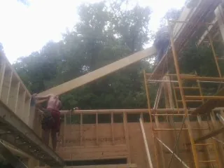 Carpenter raising a rafter beam on a new second story frame in Ponce De Leon