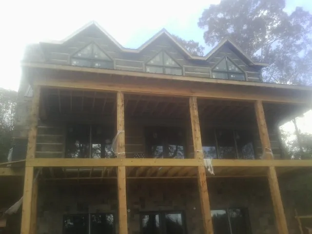 Dormers and porch framing on a large log home under construction — Roof Coating work by our crew in Ponce De Leon