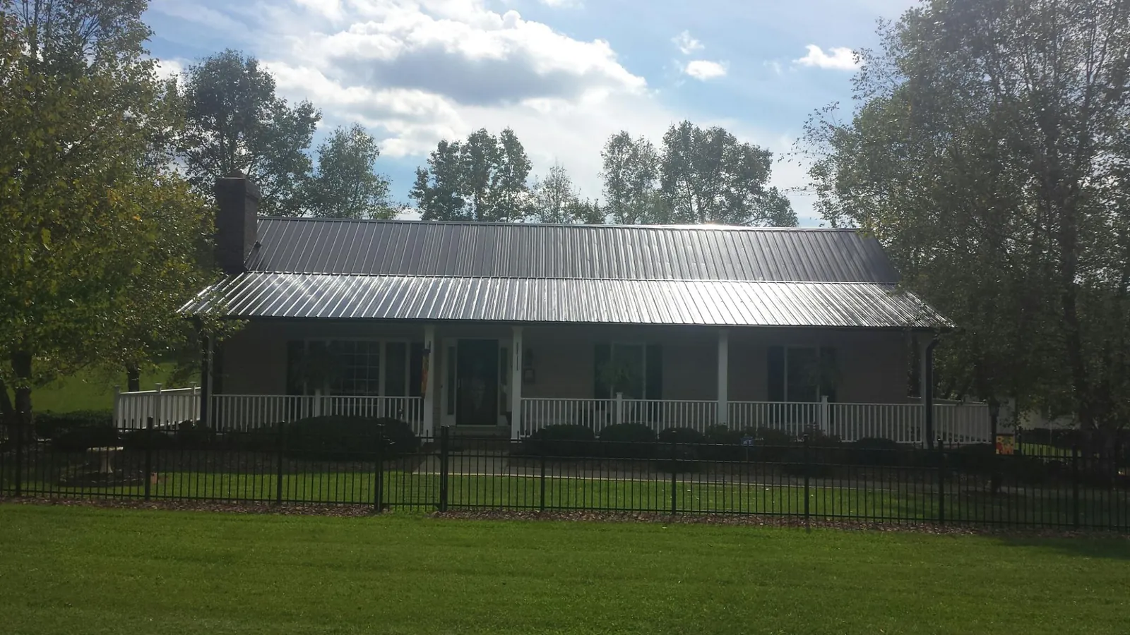 Gray metal roof on a brick ranch with a full width front porch — Gutter Guard Installation work by our crew in Ponce De Leon