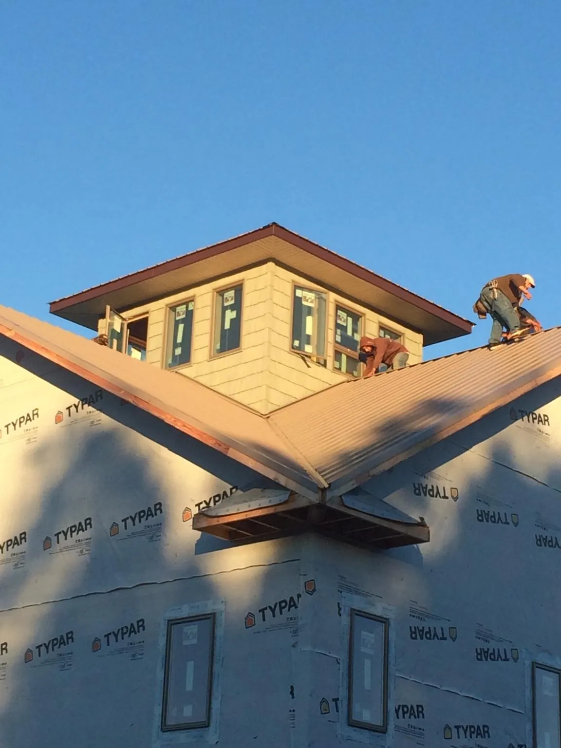Roofers working around a rooftop cupola on a new metal roof at sunset — Roof Waterproofing in Ponce De Leon by Roofing Brothers